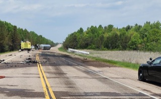 Debris scattered across a two-lane highway, emergency vehicles present