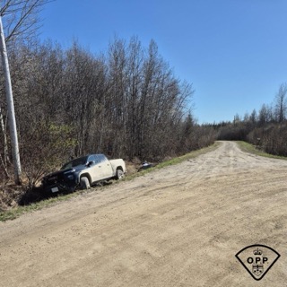 Pickup truck partially in ditch, clear blue sky, bare trees