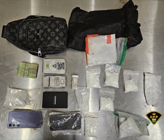 Louis Vuitton crossbody bag, cash, multiple small baggies with white powder, cell phones, wallet, cards, and a lighter.