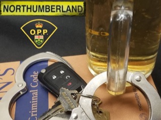 Handcuffs, keys, and a car key fob on a document. A glass of liquid is behind them.