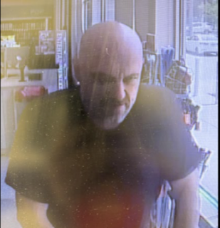 Man with a shaved head and beard looking off to the side