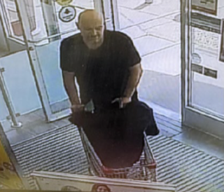 Man in black shirt and black pants, bald head, standing in a doorway