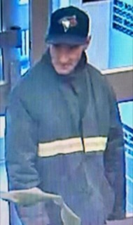 Man wearing a blue Toronto Blue Jays baseball cap and a dark green jacket with a yellow stripe.