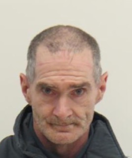 Man with short, receding hairline and stubble, looking directly at the camera