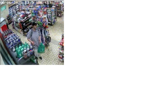 Man in a gray t-shirt reaching for drinks in a store.