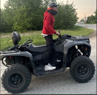 Person on a gray ATV wearing a red long-sleeved shirt, black helmet, and white shoes