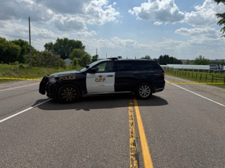 Police cruiser parked on the shoulder of a two-lane road.