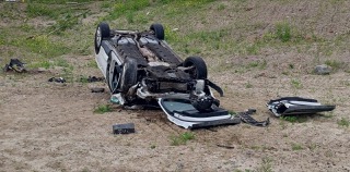 Damaged car overturned on grass.