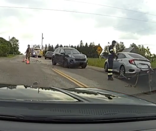 Two cars and an SUV involved in a collision on a rural road. A firefighter directs traffic.