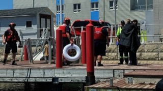 Red life ring on a dock, several people in life jackets and uniforms
