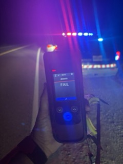 Hand holding a device displaying FAIL, #00009, 23:16