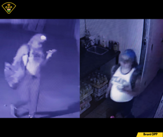 Person in a white tank top and blue jeans, standing near a door.