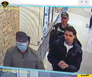 Two people wearing masks and dark clothing.