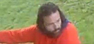 Man wearing an orange shirt, lying on grass