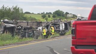 Wrecked semi-truck on its side, firefighters examining the scene