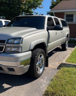 Silver extended cab pickup truck with chrome accents and off-road tires.