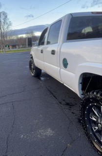 White pickup truck with black wheels and lifted suspension