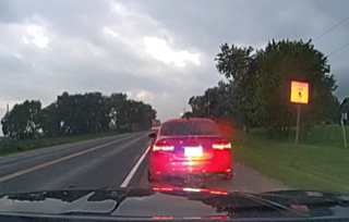 Red car driving on a wet road, overcast sky
