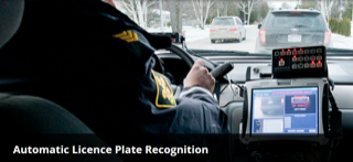Police officer operating license plate reader in a vehicle.