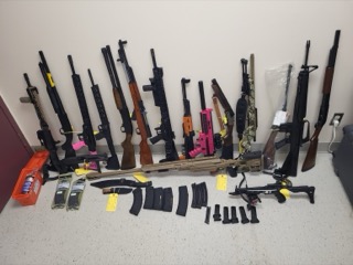 Assorted firearms and ammunition displayed on a tiled floor
