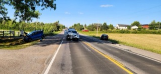 Three cars involved in a collision on a rural road.