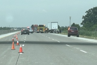 Traffic cones and vehicles stopped on a highway.