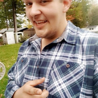 Man smiling and pointing, wearing a blue and white plaid shirt