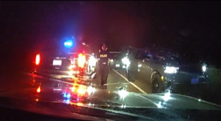 Police officer and vehicles at a nighttime accident scene.