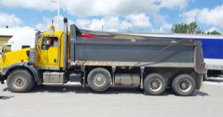 Yellow semi-truck with a black dump bed.