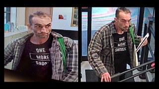 Man wearing a black t-shirt that reads "ONE MORE SNOOZE" and a plaid shirt, looking directly at the camera