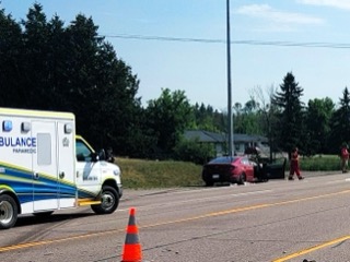 Ambulance and red car on roadside.