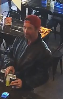 Person wearing a red beanie and black jacket holding two drinks