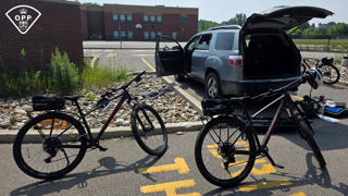 Two mountain bikes in a bike rack attached to a gray SUV.