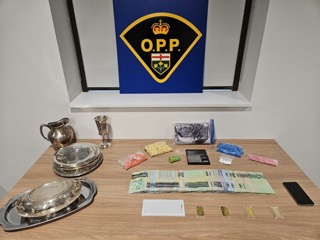 Silverware and small baggies of pills on a table, Canadian money, gold bars, a phone, and an OPP logo in the background.