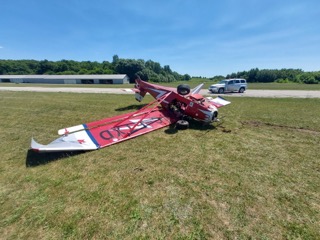 Damaged red and white airplane on grass.