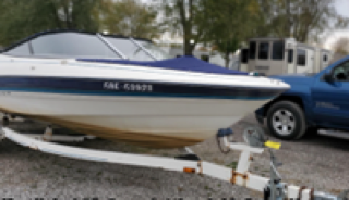 White boat on a trailer, blue accents, trailer license plate: 5AL 6999