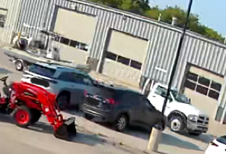 Red tractor with attachments, black SUV, white van, gray building