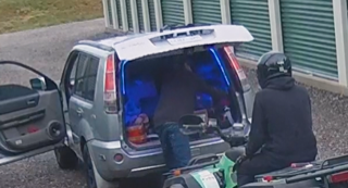 Silver SUV with blue interior lights, person in black jacket and helmet on motorcycle behind it