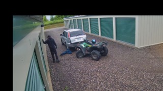 Man standing near a white SUV towing an ATV