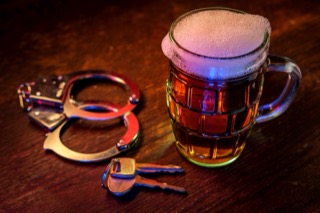 Handcuffs and keys next to a beer mug