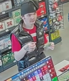 Person holding money, black vest, red shirt, black hat