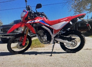 Red and white Honda CRF motorcycle on a gravel surface