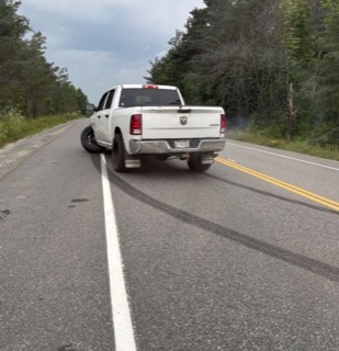 White pickup truck drifting on a road, tire smoke visible