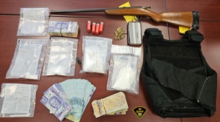 Canadian currency bundles, small baggies of white powder, shotgun, ammunition, bulletproof vest.