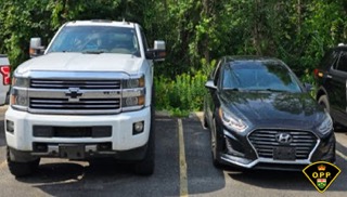 White pickup truck and black sedan parked in a lot.