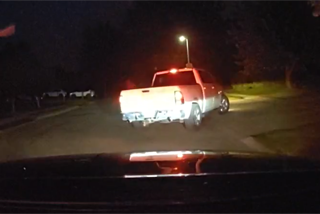 Red and white pickup truck driving on a dark road