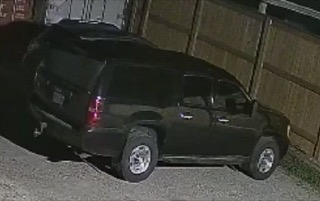 Black SUV parked on gravel.