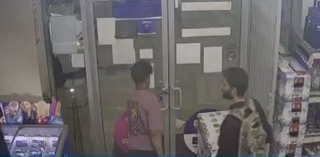 Two people standing near a door covered in papers.