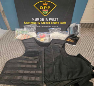 Black tactical vest and cargo pants. Bundled cash and a black ski mask visible behind.