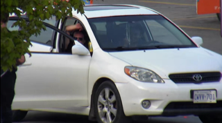 White Toyota Corolla, side view, person visible in driver's seat